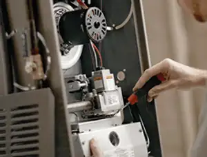 Furnace repair technician inspecting internal components and wiring in Sarasota, FL
