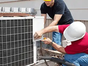 HVAC technicians repairing an outdoor AC unit on a rooftop in Sarasota, FL