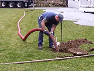 Septic pumping technician servicing a residential septic tank with a vacuum hose in Sarasota, FL
