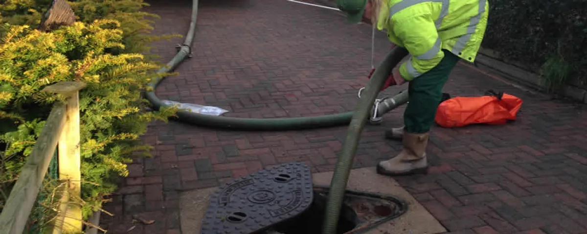 Septic tank cleaning technician servicing a septic tank with a vacuum hose in Sarasota, FL