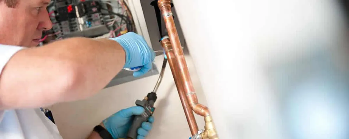 Water heater repair technician testing copper pipe connections and controls in Sarasota, FL